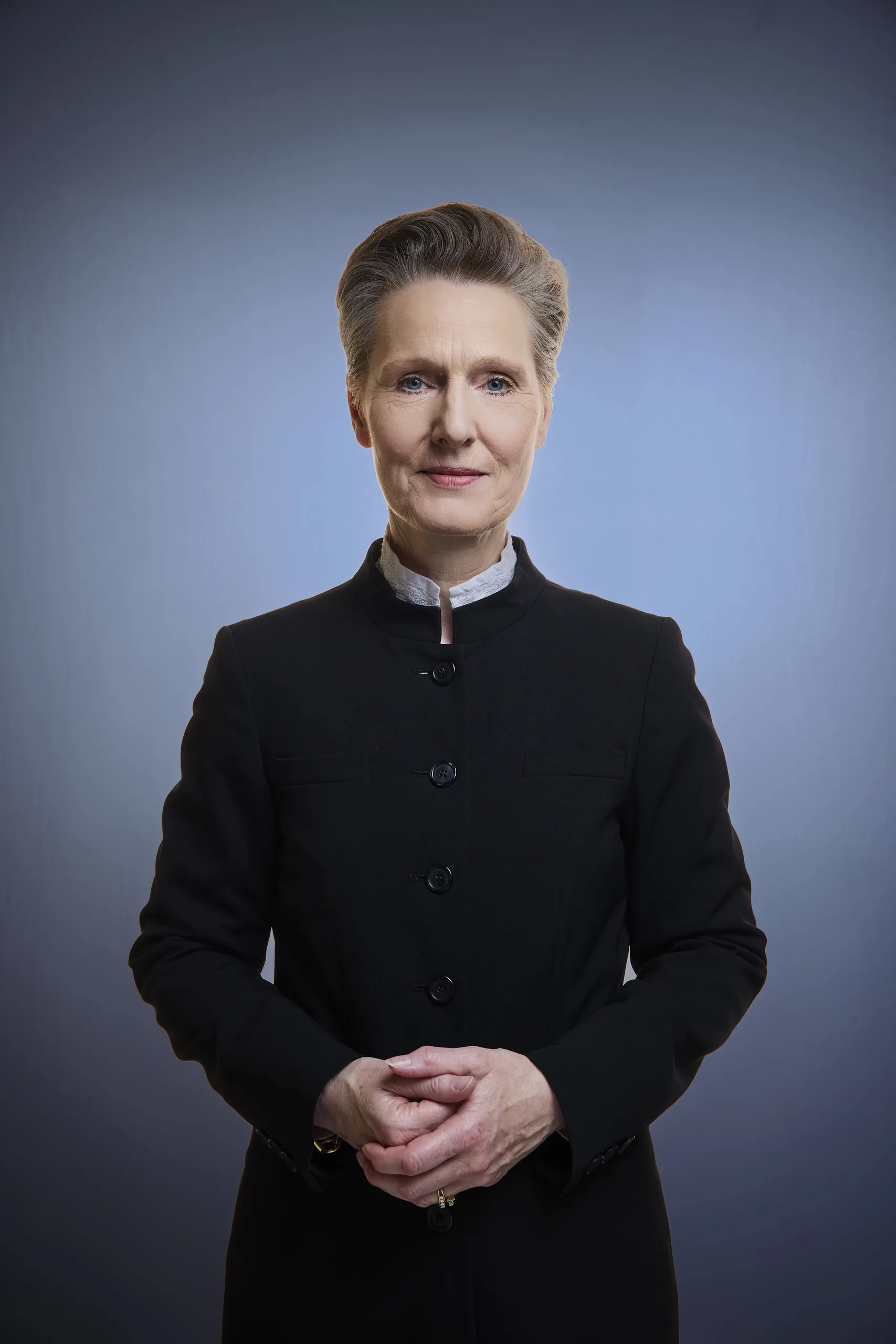 Petra Lienhop in einem vollständigen Porträt vor blauem Hintergrund